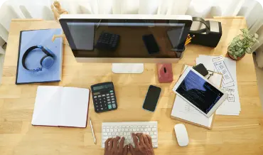 Individual engaged in typing on a computer and using a phone, highlighting custom solutions in web development.
