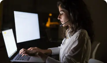 A developer woman wearing a headset and typing on a laptop, showcasing Dinoustech's dedication to transparency with expert.